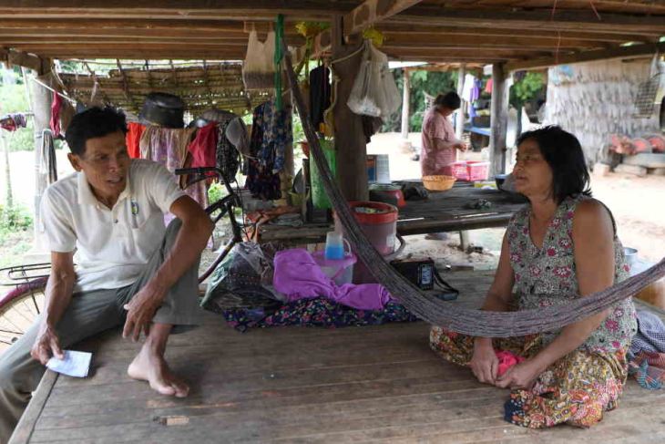 A village chief (L) speaks to a woman with microfinancing debts