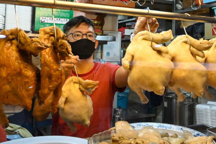 Hawker displaying chickens in Singapore
